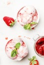 Strawberry ice cream with jam topping, decorated with green mint leaves, gray kitchen table background, top view Royalty Free Stock Photo