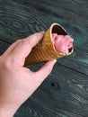 Strawberry ice cream in a waffle cone. In a manÃ¢â¬â¢s hand. Against the background of pine brushed boards painted in black and white Royalty Free Stock Photo