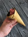 Strawberry ice cream in a waffle cone. In a manÃ¢â¬â¢s hand. Against the background of pine brushed boards painted in black and white Royalty Free Stock Photo