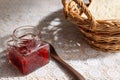 Strawberry jam in a glass bottle and breads in a basket on the table Royalty Free Stock Photo