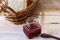 Strawberry jam in a glass bottle and breads in a basket on the table Royalty Free Stock Photo