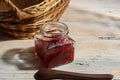 Strawberry jam in a glass bottle and breads in a basket on the table Royalty Free Stock Photo