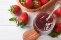 Strawberry jam. Strawberry jam in glass jar with fresh berries plate on white wooden table background, closeup. Homemade Royalty Free Stock Photo