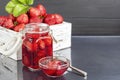 Strawberry jam in a glass jar next to fresh strawberries. On a black wooden background. Homemade winter fruit blanks. Selective Royalty Free Stock Photo