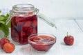 Strawberry jam in a glass jar next to fresh strawberries. On a white wooden background. Homemade winter fruit blanks. Selective Royalty Free Stock Photo