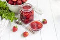 Strawberry jam in a glass jar next to fresh strawberries. On a white wooden background. Homemade winter fruit blanks. Selective Royalty Free Stock Photo