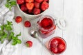 Strawberry jam in a glass jar next to fresh strawberries. On a white wooden background. Homemade winter fruit blanks. Selective Royalty Free Stock Photo