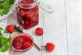 Strawberry jam in a glass jar next to fresh strawberries. On a white wooden background. Homemade winter fruit blanks. Selective Royalty Free Stock Photo