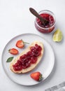 Strawberry jam on a piece of bread on a plate on a blue background with fresh berries and jar with jam Royalty Free Stock Photo