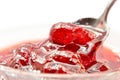 Strawberry jam is stirred with a spoon on a white background. Fruit dessert close up. Confectionery