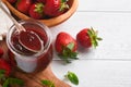 Strawberry jam. Strawberry jam in glass jar with fresh berries plate on white wooden table background, closeup. Homemade Royalty Free Stock Photo