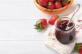 Strawberry jam. Strawberry jam in glass jar with fresh berries plate on white wooden table background, closeup. Homemade Royalty Free Stock Photo