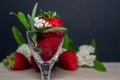 Strawberry in a little decorated glass. strawbwrries and small white flowers in a composition in the background Royalty Free Stock Photo