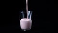 Strawberry milk shake isolated on black background. In transparent glass pour viscous pink milkshake on black background