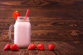 A strawberry milkshake in a mason jar. Pink smoothie on a wooden background. A yogurt with a straw and fresh berries. Copy space. Royalty Free Stock Photo