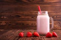 A strawberry milkshake in a mason jar. Pink smoothie on a wooden background. A yogurt with a straw and fresh berries. Copy space. Royalty Free Stock Photo