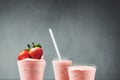 Strawberry milkshake, smoothie cocktail three glasses and fresh berries on gray concrete background.