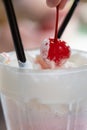 Strawberry milkshake with whipped cream and cherry on top, retro dessert topping.