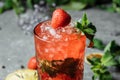 Strawberry Mojito. Cold summer mojito cocktail with strawberries, mint, lemon and ice in a glass on a table. on a dark background Royalty Free Stock Photo