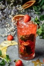 Strawberry Mojito. Cold summer mojito cocktail with strawberries, mint, lemon and ice in a glass on a table. on a dark background Royalty Free Stock Photo