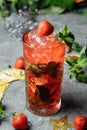 Strawberry Mojito. Cold summer mojito cocktail with strawberries, mint, lemon and ice in a glass on a table. on a dark background Royalty Free Stock Photo