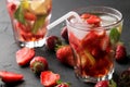 Strawberry Mojito. Cold summer mojito cocktail with strawberries, mint, lemon and ice in a glass on a black table. on a dark backg Royalty Free Stock Photo