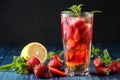 Strawberry Mojito. Cold summer mojito cocktail with strawberries, mint, lemon and ice in a glass on a blue wooden table. on a dark Royalty Free Stock Photo