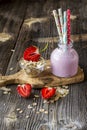 Strawberry oats milkshake for Breakfast or a snack in a glass decanter on a simple wooden background with a strawberry