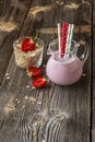 Strawberry oats milkshake for Breakfast or a snack in a glass decanter on a simple wooden background with a strawberry