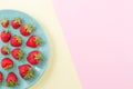 Strawberry on a plate on double pastel pink yellow background.