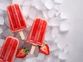 Strawberry popsicles lying on ice, with copy space.