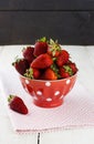 Strawberry in red bowl with a pattern in peas on a fabric napkin Royalty Free Stock Photo