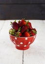 Strawberry in red bowl with a pattern in peas on a white table Royalty Free Stock Photo