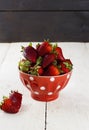 Strawberry in a red bowl with a pattern in peas on a white table Royalty Free Stock Photo