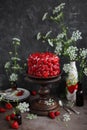 Strawberry red cake on a tall wooden stand.