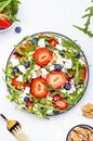 Strawberry salad with arugula, lettuce, blueberries, feta cheese and walnuts, white table. Fresh useful dish for healthy eating Royalty Free Stock Photo