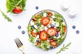 Strawberry salad with arugula, lettuce, blueberries, feta cheese and walnuts, white table. Fresh useful dish for healthy eating Royalty Free Stock Photo