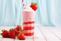 a strawberry shake with a striped paper straw