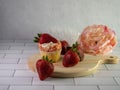 Strawberry shortcake cupcake garnished with fresh strawberries sitting on a round wooden cutting board with a handle on a white Royalty Free Stock Photo