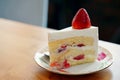 A strawberry shortcake topped with a large fresh strawberry placed in white plate and on wooden table with copy space Royalty Free Stock Photo