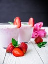 Strawberry smoothie with berries and pink flowers on white wood table and dark background. Fresh milkshake Royalty Free Stock Photo