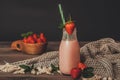 Strawberry smoothie in jar with fresh strawberries in wooden bowl