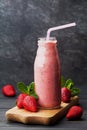Strawberry smoothie or milkshake in jar on black rustic background, healthy food for breakfast