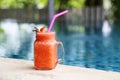 Strawberry smoothie in mug with swimming pool background in summer time Royalty Free Stock Photo