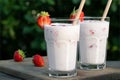 Strawberry smoothie in two glass glasses and fresh strawberries on a wooden table in the yard Royalty Free Stock Photo