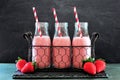 Strawberry smoothies in bottles in a vintage wire basket over dark slate