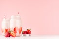 Strawberry smoothies in retro glass jars with bright sliced berries, straws on light, soft, pink background, copy space. Royalty Free Stock Photo