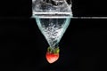 A strawberry splashing into water