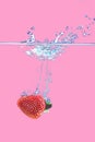 A strawberry splashing into water Isolated on pink background Royalty Free Stock Photo