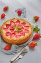 Strawberry tart on the gray kitchen background. Berries cheesecake decorated with organic fresh strawberries and mint leaves Royalty Free Stock Photo